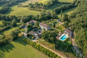 Vista aérea de una extensa propiedad con varias construcciones, una piscina y jardines cuidados.