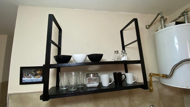 A kitchen shelf with black bowls, glasses, and a picture frame. - Downtown Apartment (VILLA MARIA)