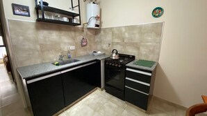 A compact kitchen with a sink, stove, and black cabinets. - Downtown Apartment (VILLA MARIA)