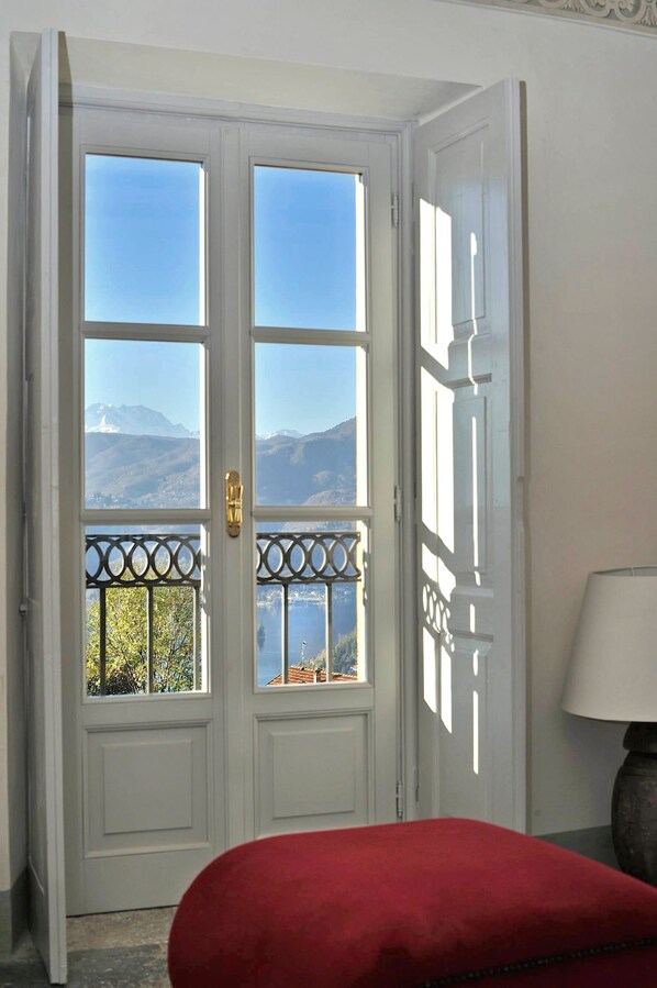 A room with a white door leading to a balcony with a mountain view.