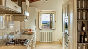 Una cocina moderna con estufa a gas, armarios blancos y un espacio para vinos.