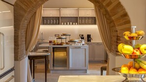 A modern kitchen with an archway, a central island with breakfast items, and a fruit display.