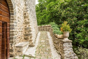 A stone staircase leading up to a wooden door, surrounded by greenery and stone walls.
