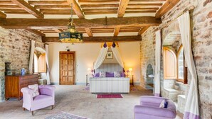A room with exposed wooden beams, stone walls, a bed with a canopy, two armchairs, and a patterned rug. - Castello Gubbio - Fifteen Bedroom Castle, Sleeps 30 (Gubbio)