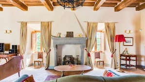 A cozy living room with a fireplace, wooden beams, and striped curtains. - Castello Gubbio - Fifteen Bedroom Castle, Sleeps 30 (Gubbio)