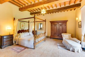 A traditional bedroom with a four-poster bed, a wooden cabinet, and a bench.