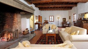 A cozy living room with a fireplace, a sofa set, a coffee table, and a dining area with chairs. - Casa Poggio - Four Bedroom Villa, Sleeps 12 (Cassia)