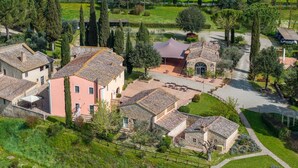 A traditional stone building with a pink facade, surrounded by well-maintained gardens and tall trees.