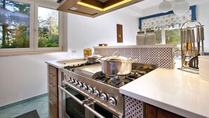 Una cocina moderna con estufa de acero inoxidable, encimeras blancas y un salpicadero con diseño.