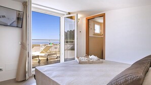Un dormitorio con cama, ventana y vistas a un balcón con mobiliario exterior.