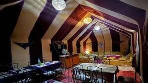 A tent-style room with a dining area, a sofa, and a small kitchen area.