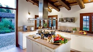 Una cocina moderna con una isla central, vigas de madera y vistas al jardín.