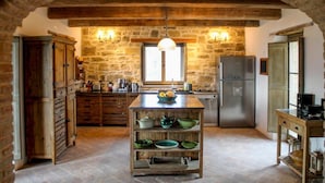 Une cuisine rustique avec des murs en pierre, des armoires en bois et un îlot central agrémenté de bols.
