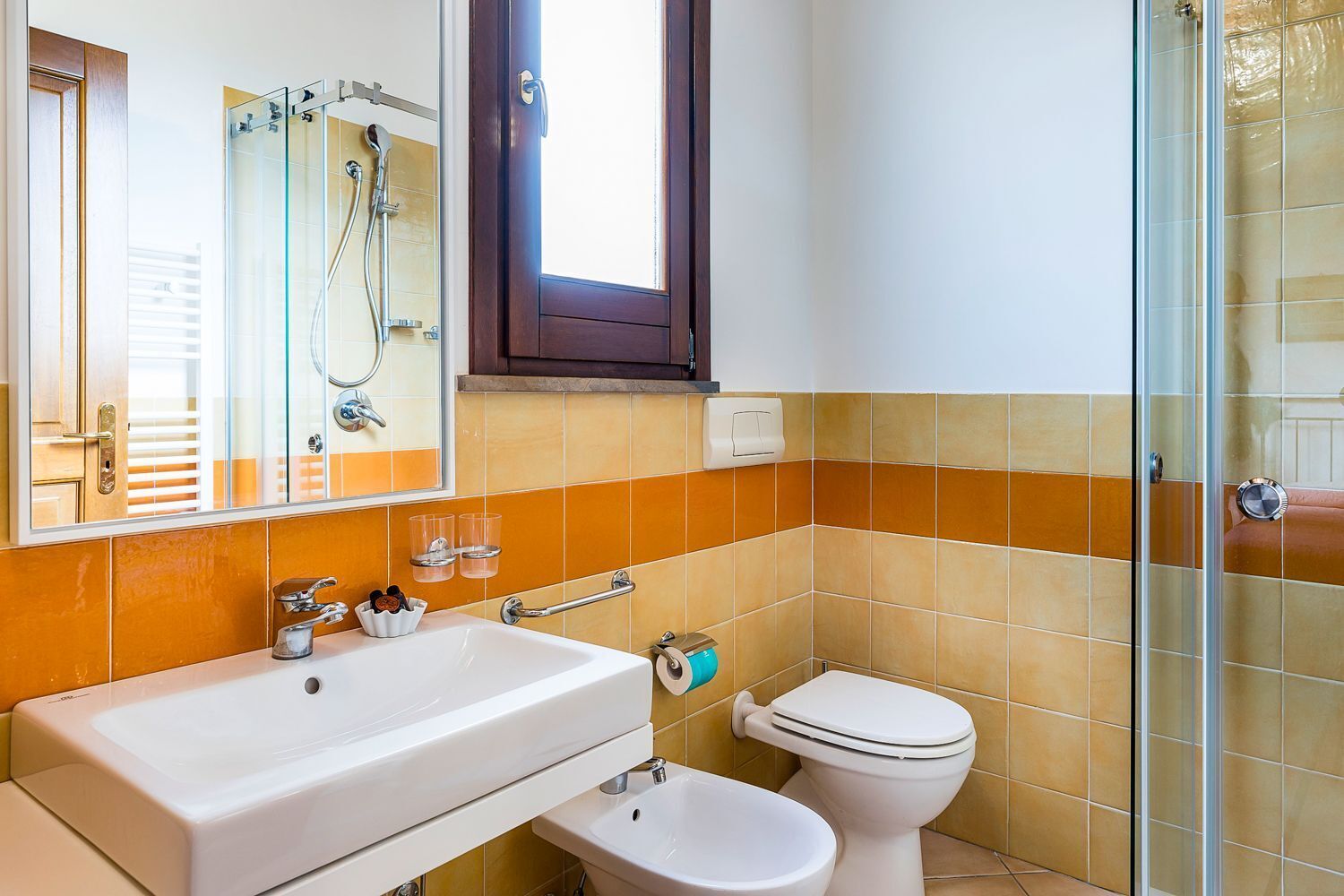Une salle de bain avec un lavabo blanc, des toilettes blanches et une douche à parois de verre.