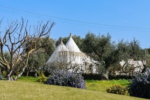 A white conical structure with a pointed roof, surrounded by a grassy field and various trees. - La Piccola Pietrina - One Bedroom Villa, Sleeps 2 (Ostuni)