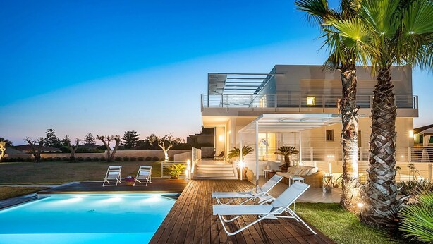 Een modern huis met een zwembad, terrasmeubels buiten en een overdekte patio.