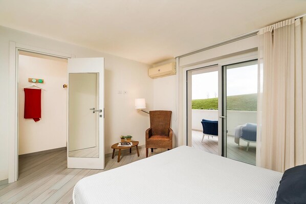Une chambre d’hôtel avec un lit, une chaise, une petite table avec une lampe, une serviette rouge et une vue sur l’extérieur.