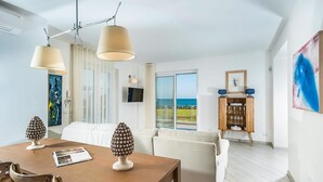 Een moderne woonkamer met een eethoek, grote ramen en uitzicht op zee.