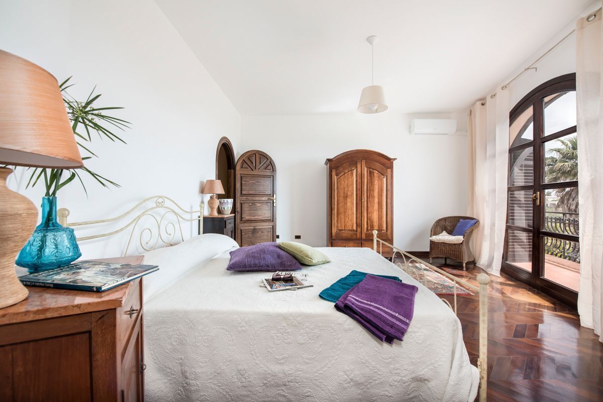 Una camera da letto con un letto, un armadio in legno, una sedia in vimini e una finestra vista.