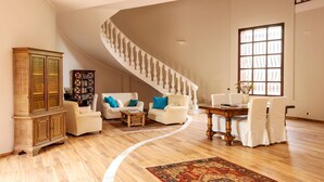 A spacious living room with a curved staircase, a dining area, and a large window. - Villa Amina - Four Bedroom Villa, Sleeps 10 (Mazara del Vallo)