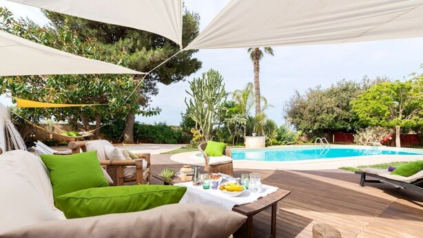 An outdoor deck with a pool, wicker furniture, and a table with a banana and drinks. - Villa Amina - Four Bedroom Villa, Sleeps 10 (Mazara del Vallo)