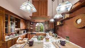 A kitchen with wooden cabinets, marble countertops, and hanging light fixtures. - Villa Amina - Four Bedroom Villa, Sleeps 10 (Mazara del Vallo)