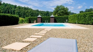 Ein Schwimmbecken mit Steinstufen, umgeben von Kies und Pflanzen.