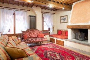 A traditional living room with a patterned sofa, a red rug, and a fireplace.