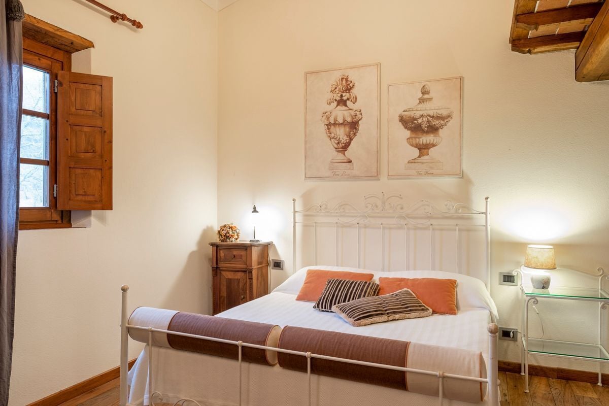 A bedroom with a bed, a nightstand, a lamp, and two framed pictures on the wall.
