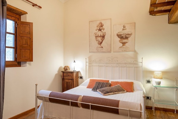 Ein Schlafzimmer mit einem Bett, einem Nachttisch, einer Lampe und zwei gerahmten Bildern an der Wand.