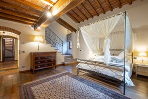 Ein Schlafzimmer mit einem Himmelbett, einem Holzschrank, einer Treppe und einem gemusterten Teppich.