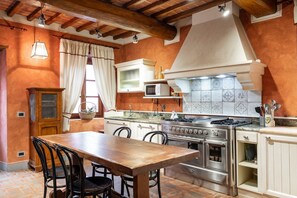 A kitchen with a wooden table, chairs, a stove, oven, and cabinets.