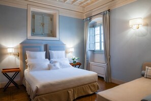 Una habitación de hotel con una cama grande, dos mesitas de noche, una lámpara de pared y cortinas en la ventana.