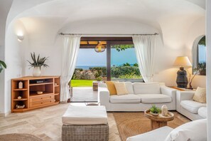 Un salon spacieux avec un grand canapé, un meuble en bois et une vue sur l’océan.