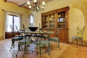 A dining area with a round table, four chairs, a chandelier, and a wooden cabinet with glass doors. - Villa Cecconi - Twelve Bedroom Villa, Sleeps 24 (Poggibonsi)