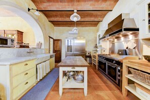A kitchen with a central island, a stove, oven, and a microwave.