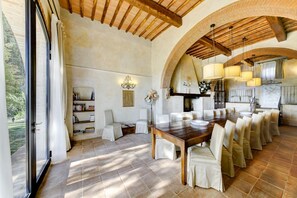 Un vaste espace dédié à la salle à manger, avec une longue table en bois et de nombreuses chaises, une cheminée et une vue sur l’extérieur.
