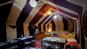 A tent-style room with a dining area, a sofa, and a small kitchen area.
