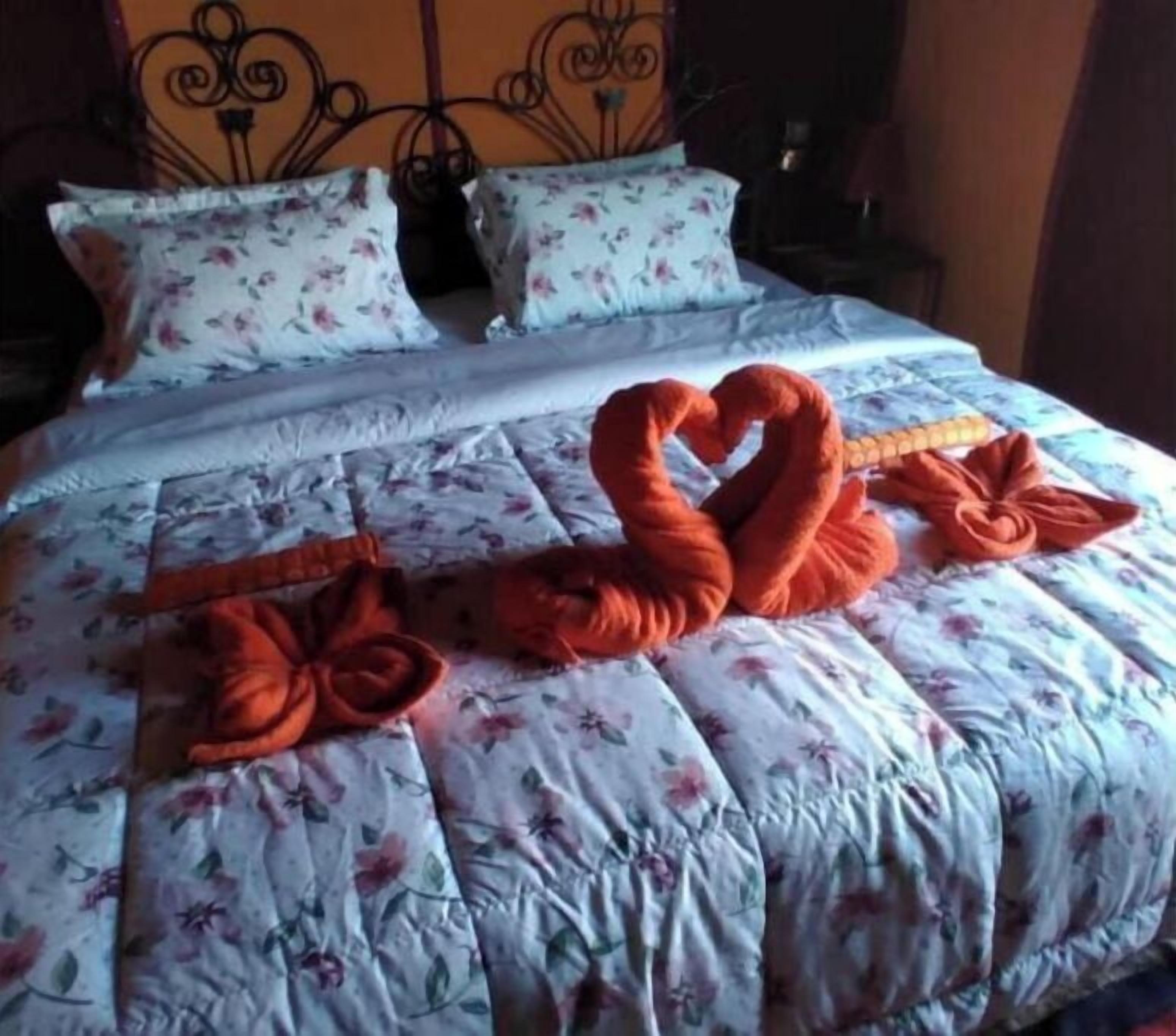 Cama com roupa de cama florida e toalhas em formato de coração.