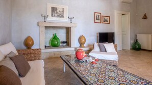 Una sala de estar con chimenea, un sofá, una mesa de centro y jarrones decorativos.