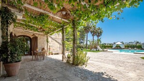 Un patio empedrado con pérgola, mobiliario exterior y zona de piscina.