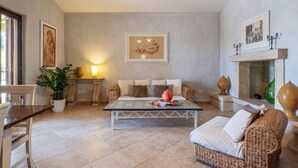 Una sala de estar con sofá, mesa de centro, chimenea y una obra de arte enmarcada en la pared.