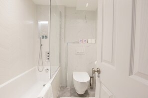 A modern bathroom with a glass-enclosed shower, a white toilet, and a marble-tiled wall. - Stylish 1BDR Retreat Steps from Portobello Road (London)