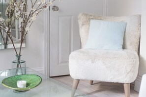 A room with a glass table, a white chair with a fluffy seat, a green bowl, and a white candle. - Sleek 1BDR Retreat Near Portobello Road (London)