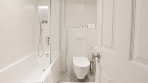 Un baño moderno con ducha, inodoro y cabina de ducha con mampara de vidrio.
