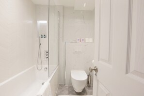 Une salle de bain moderne équipée d’une douche, de toilettes et d’un espace douche séparé par des parois en verre.