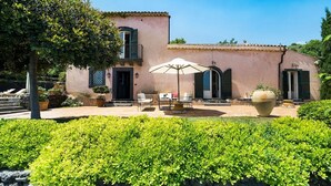 Une villa rose dotée d’un patio, de mobilier d ’extérieur et d’un grand bac à fleurs.