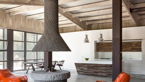 Ein modernes Interieur mit Kamin aus Stein, Sitzecke und Küche.