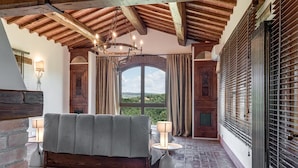 Quarto com uma cama grande, um candelabro e vista para o exterior.