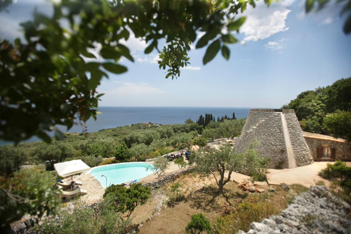 Ein Poolbereich mit einer Steinstruktur und Blick auf das Meer.